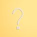 White pills arranged into a question mark shape on a vibrant yellow background.