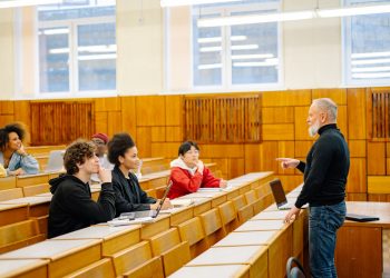 A diverse group of university students engaging with a professor during a classroom lecture.