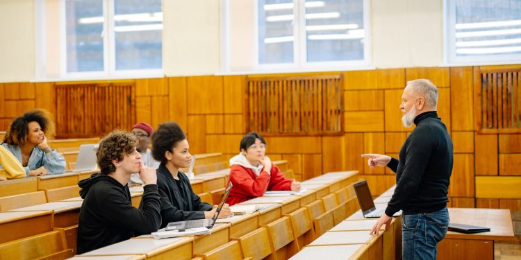 A diverse group of university students engaging with a professor during a classroom lecture.