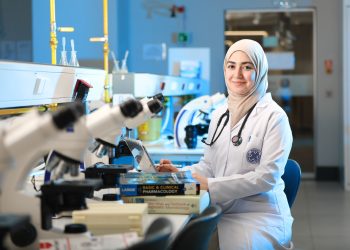 A female scientist in a laboratory setting, conducting research with microscopes and reference books.