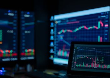 Monitors displaying stock market charts in a dimly lit room, perfect for finance and trading themes.