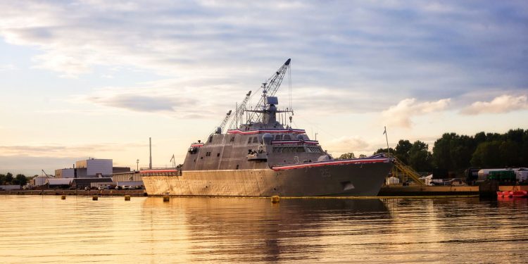 A warship docked in a serene harbor in Marinette, WI, during a golden sunset.