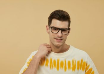 Confident man posing with fashionable eyewear against a warm background.