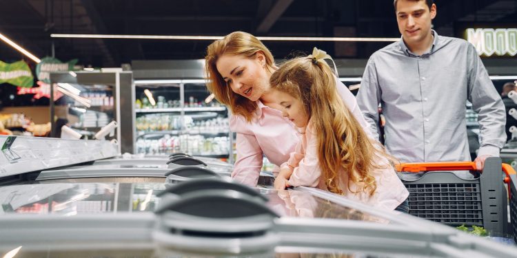 A happy family shopping in the supermarket's freezer section, emphasizing togetherness and love.