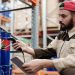 Male warehouse worker scanning barrels with a tablet for inventory management.