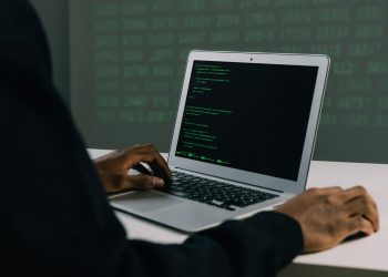 A focused adult working on a laptop demonstrates modern cybersecurity and coding skills indoors.