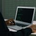 A focused adult working on a laptop demonstrates modern cybersecurity and coding skills indoors.