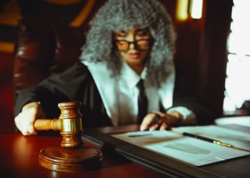 Female judge in a courtroom setting, focusing on legal documents with a gavel.