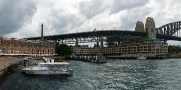 Panorama of the buildings that were once warehouses in Campbell's Cove (The Rocks district) and the Sydney Harbour Bridge (28480796454).jpg