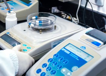 Close-up of laboratory equipment with capsules, capturing pharmaceutical analysis.
