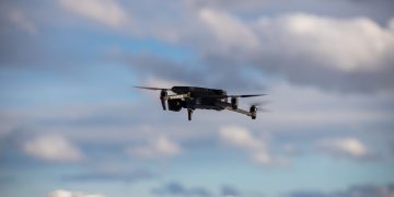 Aerial view of a drone flying over snow-covered mountains with dramatic clouds.