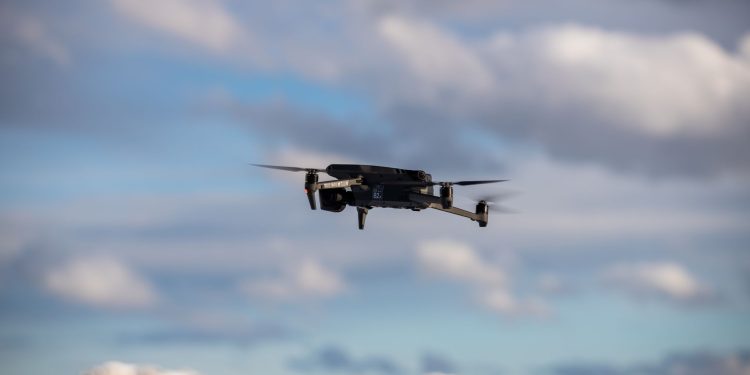 Aerial view of a drone flying over snow-covered mountains with dramatic clouds.