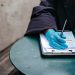 Crop anonymous ethnic female physician in disposable glove with paper on clipboard working at table in daylight