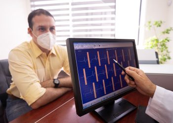 Medical consultation as a doctor reviews ECG results with a masked patient in a clinic setting.
