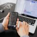 Person analyzes stock data with a smartphone and laptop, indoors.