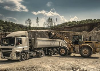 Excavator and truck working together in a quarry, showcasing industrial equipment and operations.