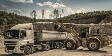 Excavator and truck working together in a quarry, showcasing industrial equipment and operations.