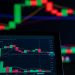 Close-up of a digital trading chart with candlestick patterns and market analysis in a dark setting.