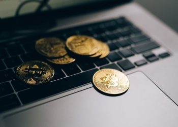 Close-up of golden Bitcoins placed on a laptop keyboard, symbolizing digital currency and modern finance.