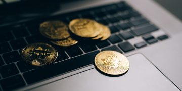 Close-up of golden Bitcoins placed on a laptop keyboard, symbolizing digital currency and modern finance.