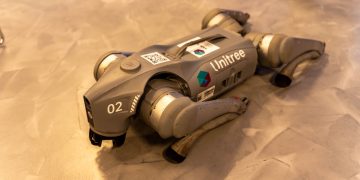 A Unitree robot dog resting on an indoor concrete floor.