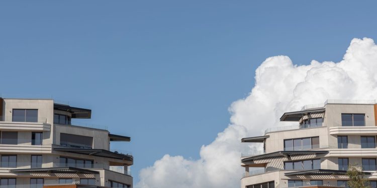 Contemporary urban architecture under a bright blue sky with clouds.