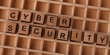 Wooden letter blocks spelling 'CYBER SECURITY' on a wooden grid background for data protection themes.