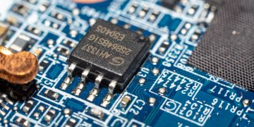 Detailed macro image of a microchip mounted on a blue circuit board.