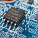 Detailed macro image of a microchip mounted on a blue circuit board.