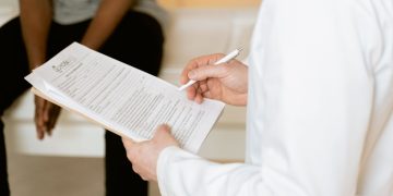 Healthcare professional reviews medical form during patient consultation in a clinic setting.